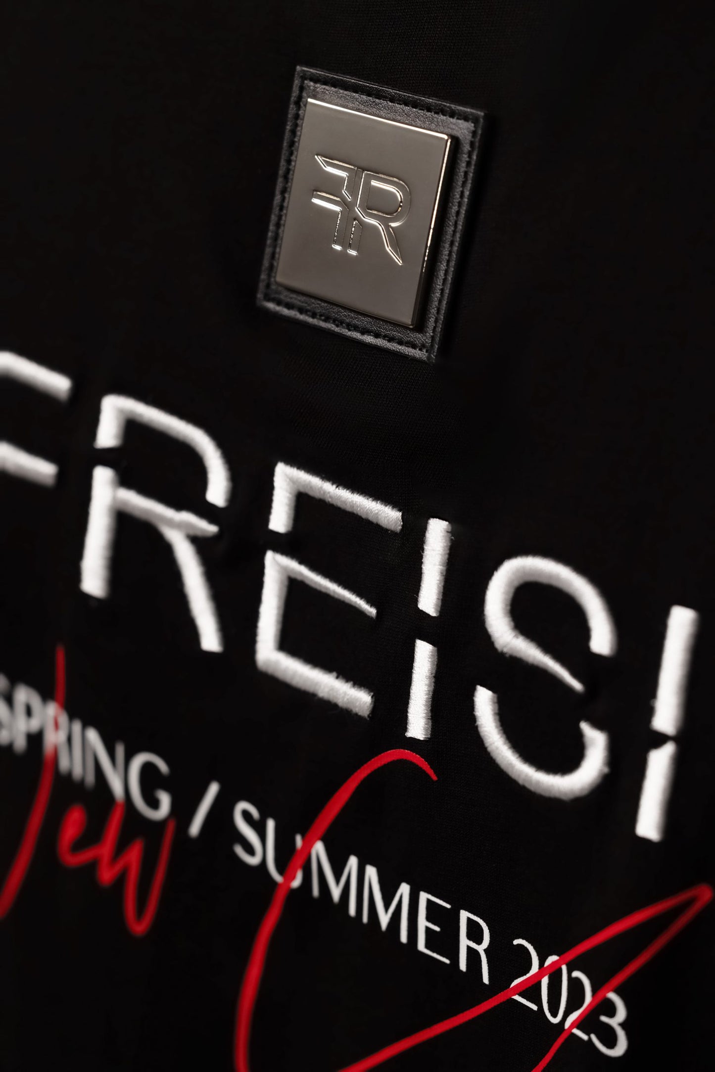 A branded gold metal and leather label on the reverse, close to the embroidered FREISI logo, marks this T-shirt as a symbol of authentic craftsmanship and sophistication